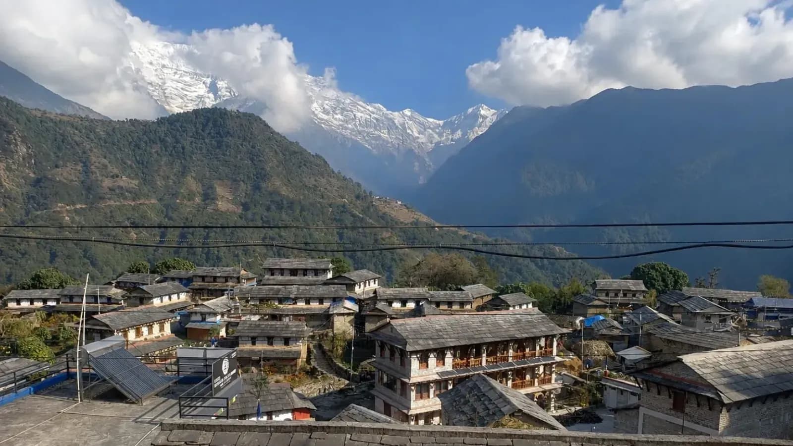 Traditional stone-roofed houses in Ghandruk village with Annapurna mountain range in the background.